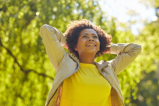 concept de personnes, de race, d'origine ethnique et de portrait - heureuse jeune femme afro-américaine dans le parc d'été