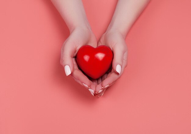 Concept de personnes, de relations et d'amour - gros plan des mains en coupe de la femme montrant un coeur rouge