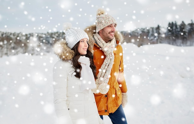 concept de personnes, de saison, d'amour et de loisirs - couple heureux marchant sur fond d'hiver