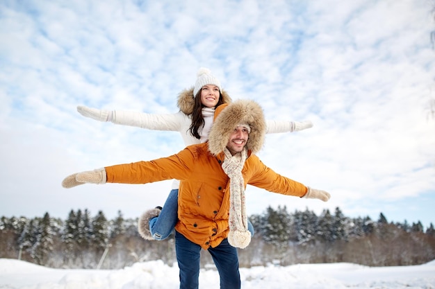 concept de personnes, de saison, d'amour et de loisirs - couple heureux s'amusant sur fond d'hiver