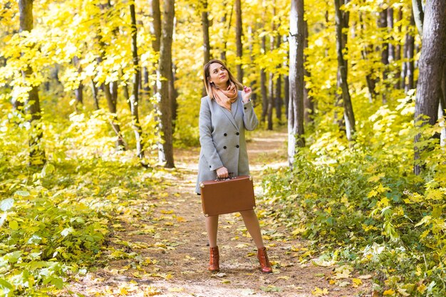 Concept de personnes, de saison et de nature - jeune femme marchant dans le parc automne avec valise