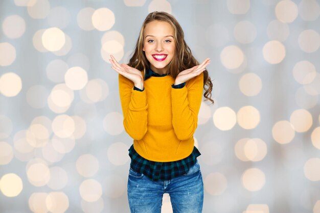 Photo concept de personnes, de style et de mode - heureuse jeune femme ou adolescente en vêtements décontractés s'amusant sur fond de lumières de vacances