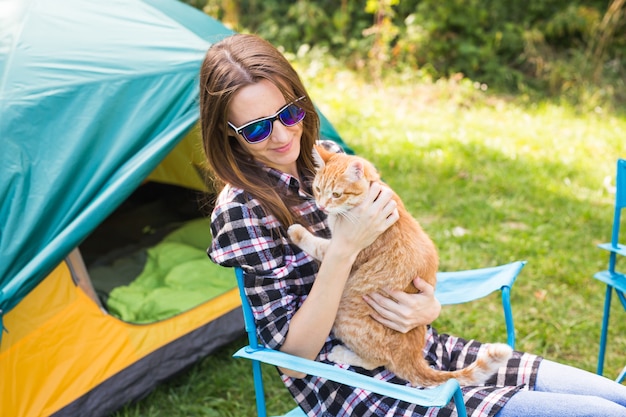 Concept de personnes, tourisme et nature - Femme à lunettes de soleil caressant un chat assis près de la tente.