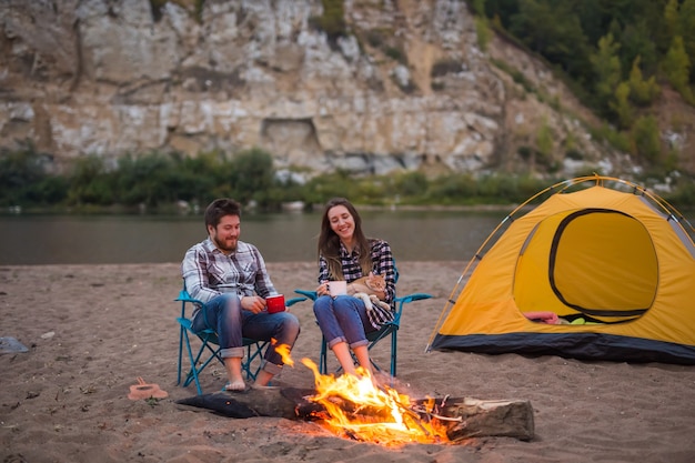 Concept de personnes, de tourisme et de nature - Soirée romantique, l'homme embrasse une femme assise près d'un feu de camp.