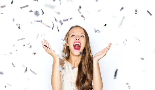 concept de personnes, de vacances, d'émotion et de glamour - heureuse jeune femme ou adolescente en robe de soirée avec des paillettes et des confettis à la fête