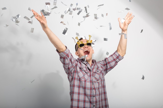 Concept de personnes, de vacances et de fête - Homme cool en chemise à carreaux sur un mur blanc avec des confettis.