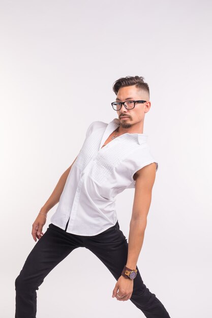 Concept de personnes, de vêtements et de style - jeune bel homme sexy posant en chemise blanche sur une surface blanche