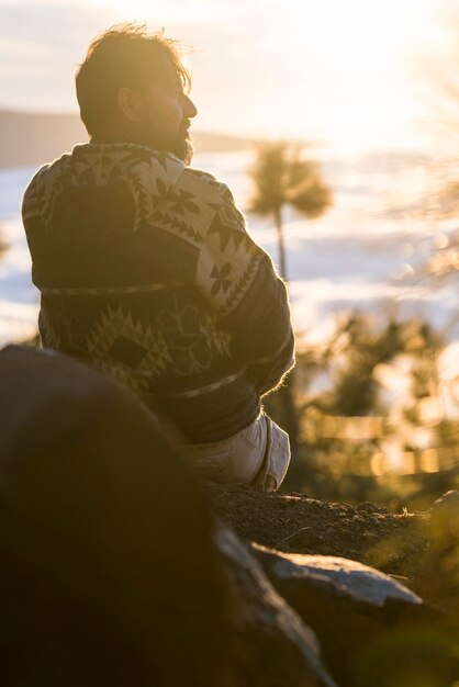 Concept de personnes et de vie en plein air nature homme assis sur les rochers et profiter du magnifique coucher de soleil et du paysage en arrière-plan montagnes tourisme vacances style de vie