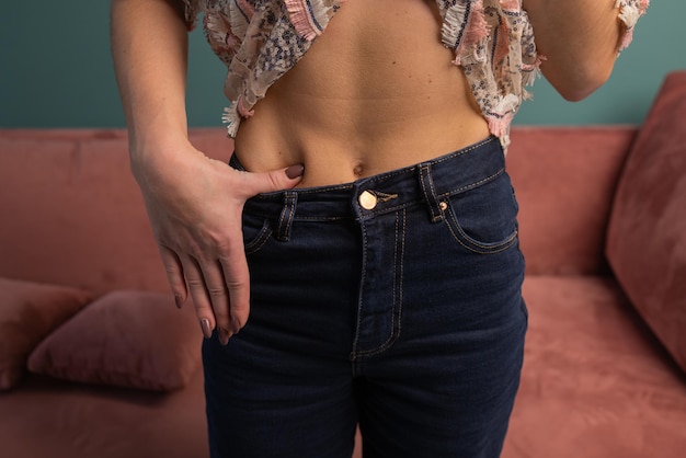 Concept de perte de poids et d'image corporelle. Une jeune femme montre sa perte de poids et porte son vieux jean. Slim Girl in Big Jeans montrant comment elle perdait du poids lorsqu'elle a commencé à manger des aliments sains.