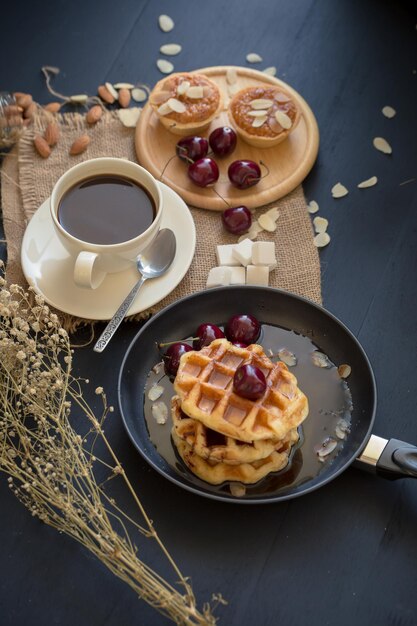 Le concept de petit déjeuner au café comprend des tartes croustillantes avec des gaufres d'amande et des cerises fraîches