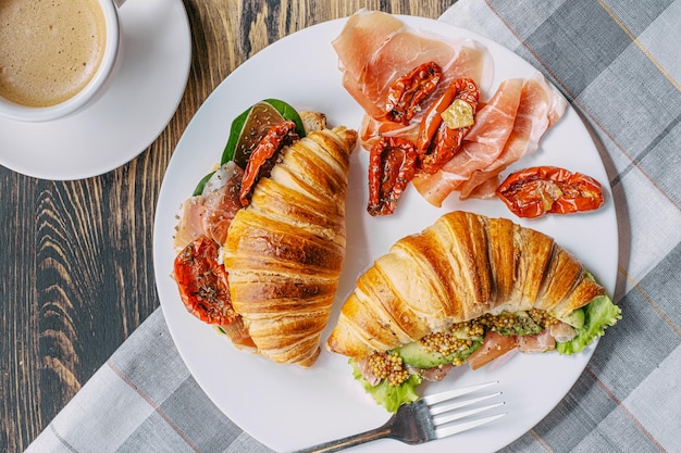 Le concept d'un petit-déjeuner copieux et savoureux de croissants frais classiques avec une variété de garnitures de ricotta jamon avocat fraises tomates séchées et moutarde française