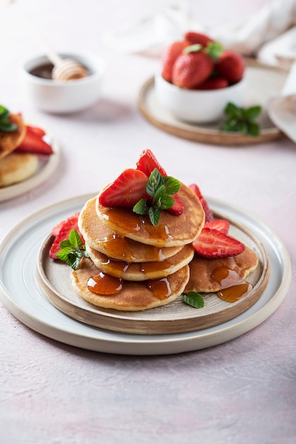 Concept de petit-déjeuner avec crêpes, miel, fraise et menthe, image de mise au point sélective