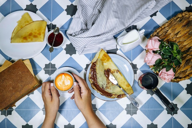 Photo concept de petit-déjeuner matinal femme mangeant des crêpes farcies au chocolat sur une assiette bleue avec f