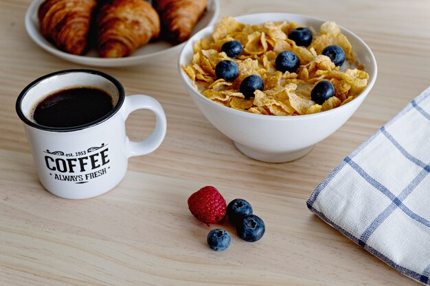 Concept de petit-déjeuner sain avec café yogourt fruits rouges et croissant sur table en bois