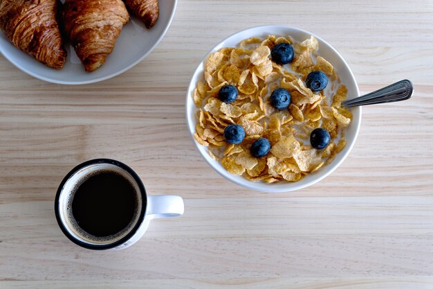 Concept de petit-déjeuner sain avec café yogourt fruits rouges et croissant sur table woodden