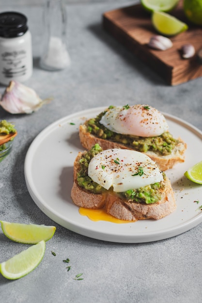 Concept de petit déjeuner sain. deux toasts avec du pain de grains entiers avec du guacamole d'avocat et un œuf poché, de l'ail et du citron vert. mode de vie sain.