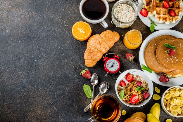 Concept De Petit Déjeuner Sain Manger Divers Aliments Du Matin - Crêpes Gaufres Croissant Sandwich à L'avoine Et Granola Avec Yaourt Fruits Baies Café Thé Jus D'orange Fond Rouillé Foncé