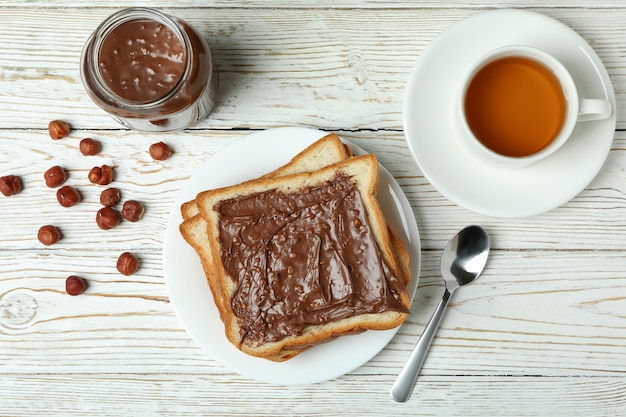 Concept de petit déjeuner savoureux avec de la pâte de chocolat sur une table en bois blanche