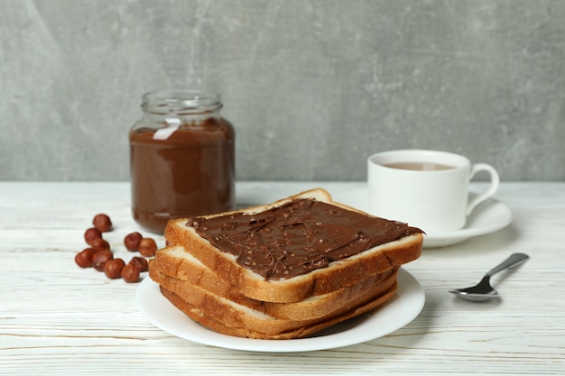 Concept de petit déjeuner savoureux avec de la pâte de chocolat sur une table en bois blanche