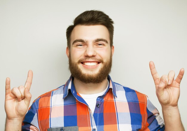 Photo et le concept de peuple jeune homme barbu montrant un geste lourd sur un fond gris