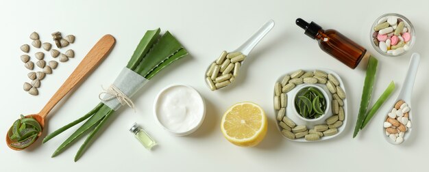 Concept de pilules d'herbes et de cosmétiques à l'aloès sur fond blanc