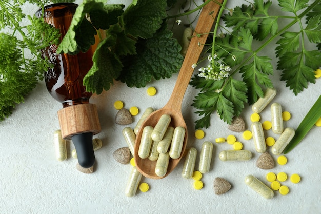 Concept de pilules de phytothérapie sur table texturée blanche, vue du dessus