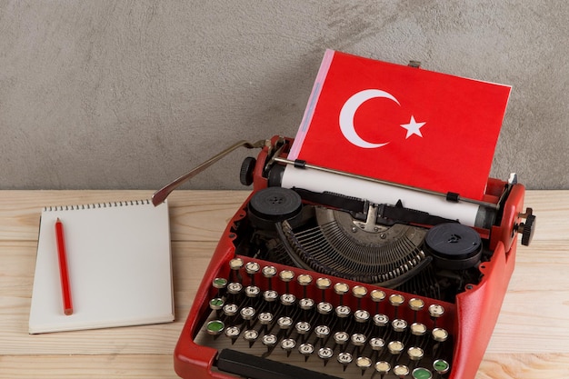 Concept politique, d'information et d'éducation - machine à écrire rouge, drapeau de la Turquie, carnet sur fond de ciment gris