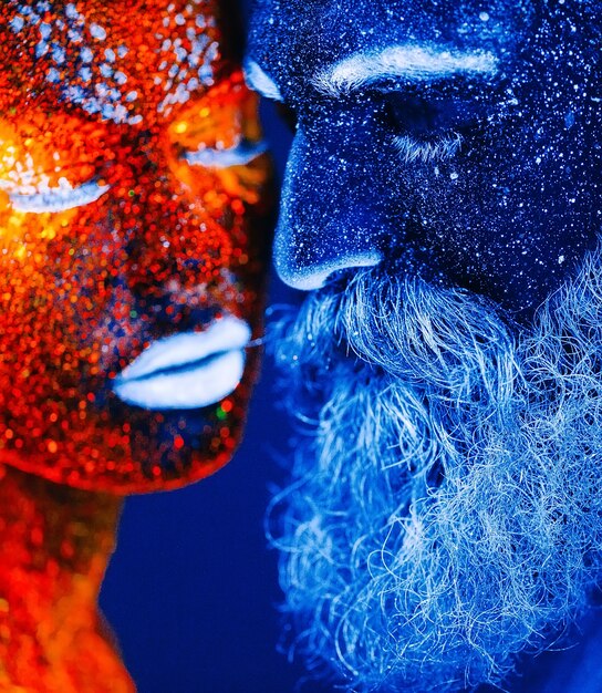 Concept. Portrait d'un homme et d'une femme barbus peints dans une poudre ultraviolette.
