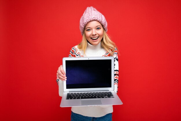 Concept portrait shot of beautiful smiling blonde young woman holding ordinateur portable avec vide