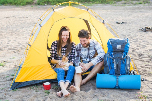 Concept pour animaux de compagnie, tourisme d'été et nature - jeune couple assis avec un chat près d'une tente.