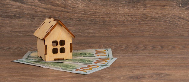 Concept de prêt hypothécaire avec modèle de maison en bois et billets de 100 dollars