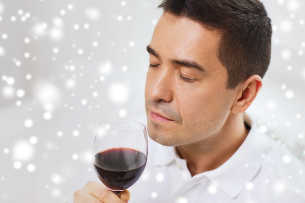 concept de profession, de boissons, de loisirs et de personnes - homme heureux buvant et sentant le vin rouge du verre sur l'effet de neige