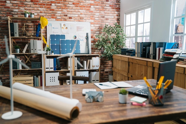 Photo concept de profession avec bureau d'architecte et outils avec fond de mur de brique rouge avec personne. bâtiment vert avec intérieur de bureau en bois moulin à vent énergie éolienne écologique. lieu de travail de l'entreprise d'ingénieurs.