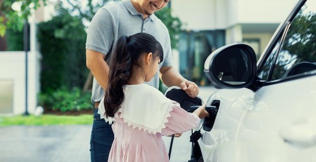 Concept progressif de père et fille avec voiture EV et borne de recharge domestique