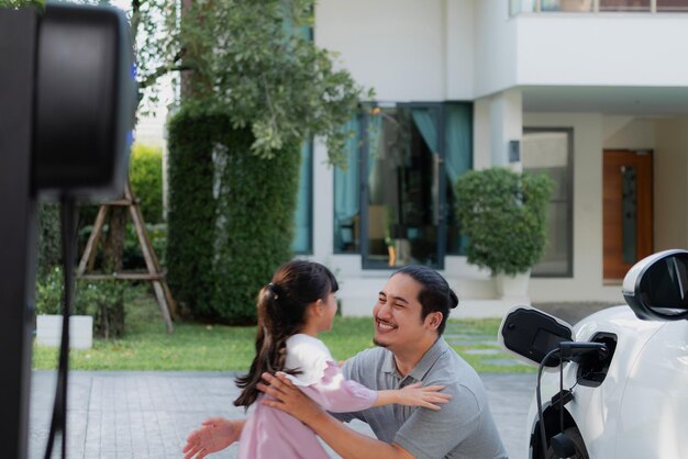 Concept progressif de père et fille avec voiture EV et borne de recharge domestique