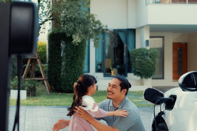 Concept progressif de père et fille avec voiture EV et borne de recharge domestique