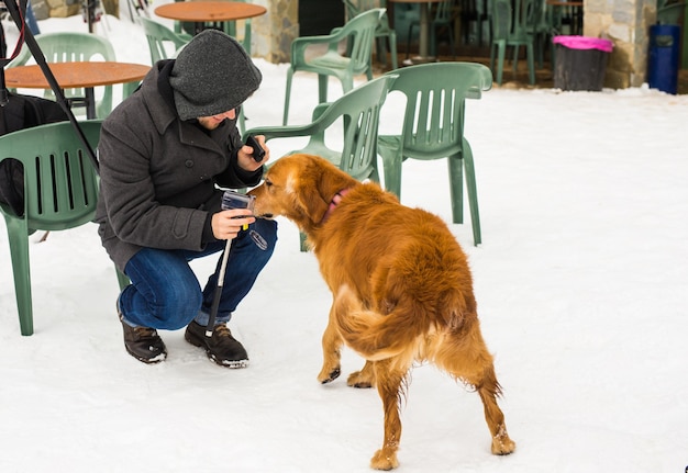 Concept de propriétaire d'animal de compagnie, de chien et de personnes - Jeune homme caucasien souriant et chien en plein air en hiver.