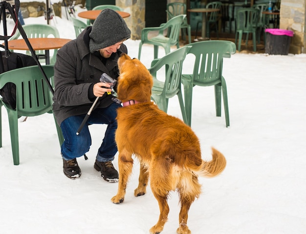 Concept de propriétaire d'animal de compagnie, de chien et de personnes - Jeune homme caucasien souriant et chien en plein air en hiver.