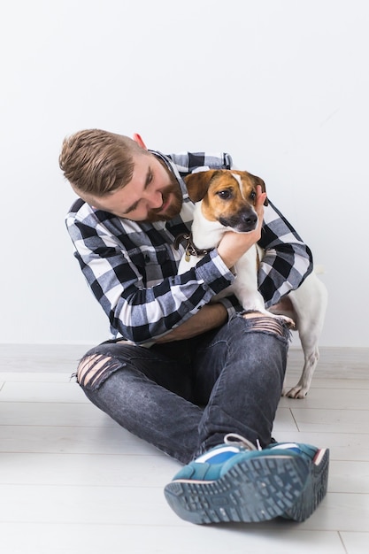 Concept de propriétaire d'animaux de compagnie - Un homme joyeux attrayant en chemise à carreaux détient un animal de compagnie préféré. Heureux homme barbu