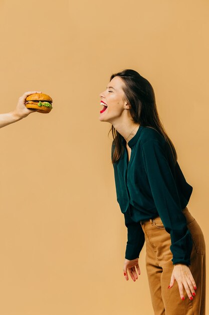 Concept de publicité de restauration rapide Une fille avec un hamburger sur un fond coloré