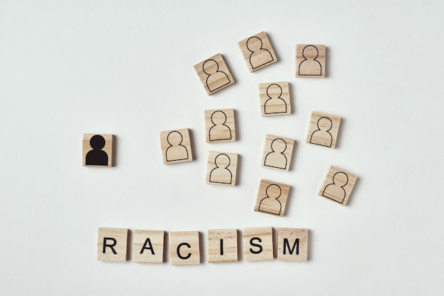 Photo concept de racisme et de malentendu entre les personnes, préjugés et discrimination. bloc de bois avec une figure noire blanche séparée des blancs et du racisme mot