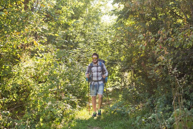 Concept de randonnée, tourisme et nature - jeune voyageur avec sac à dos debout sur la forêt