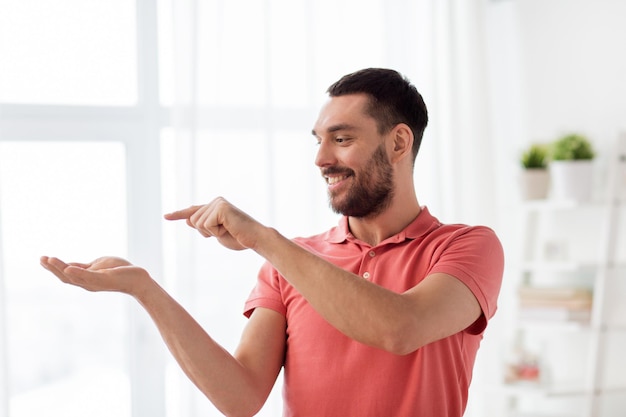 concept de réalité virtuelle, de divertissement et de personnes - homme heureux tenant et touchant quelque chose d'imaginaire sur la paume à la maison