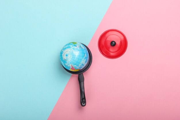 Concept de réchauffement climatique. Mini globe dans un jouet pan sur un mur pastel bleu-rose Vue de dessus. Minimalisme. Problèmes climatiques de notre temps. Vue de dessus