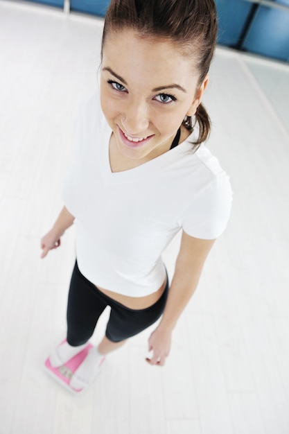 concept de régime heureux avec une jeune femme sur une échelle rose au club de gym sport fitnes