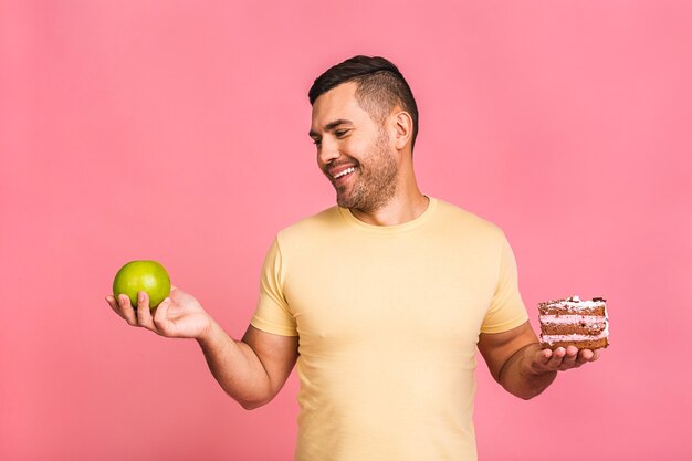 Concept de régime. Jeune homme pensant quoi manger entre une pomme et un gâteau