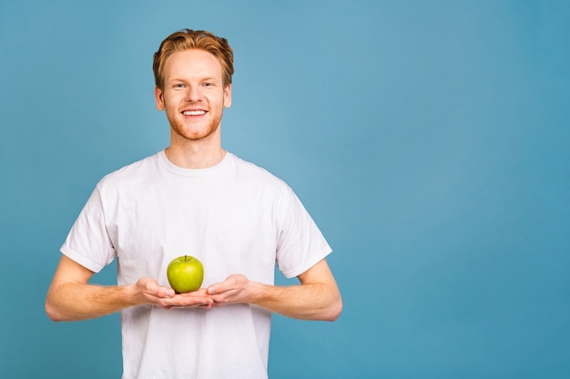 concept de régime et mode de vie sain. joyeux beau jeune homme mangeant une pomme,