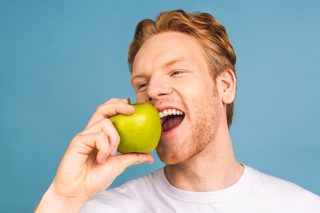 concept de régime et mode de vie sain. joyeux beau jeune homme mangeant une pomme,