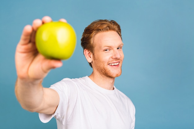concept de régime et mode de vie sain. joyeux beau jeune homme mangeant une pomme,