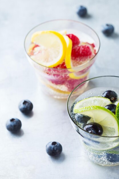 Concept de régime de nutrition saine de remise en forme de soins de santé Frais frais citron citron vert baies framboise myrtille cocktail d'eau infusée boisson détox limonade pour les jours de printemps été